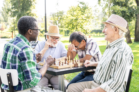 Group of senior friends playing chess at the park