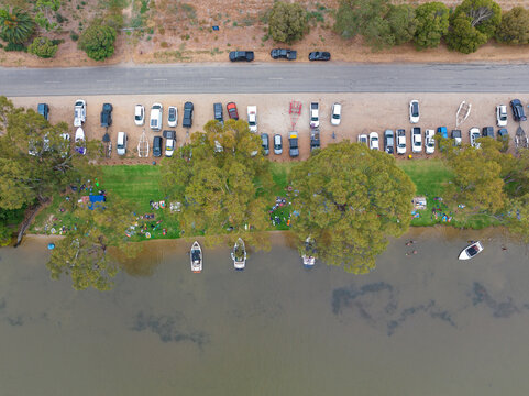 Aerial view of cars and speed boats lining the shore of an inland river