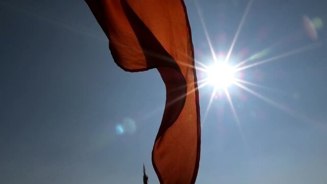 Closeup of a saffron flag fluttering against the sunlight