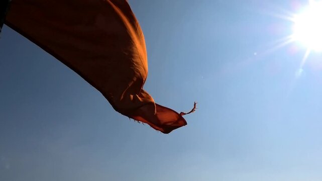 Closeup of a saffron flag fluttering against the sunlight