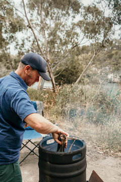 Man putting bark into a camp fire in the outdoors.