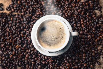 Fototapeta premium Steaming Coffee Cup Surrounded by Roasted Beans