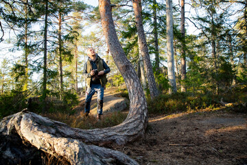 Fototapeta premium Travel content creator scouting forest location and using vintage camera for authentic storytelling. Adventure travel, Eco-mindfulness and outdoor lifestyle concept.