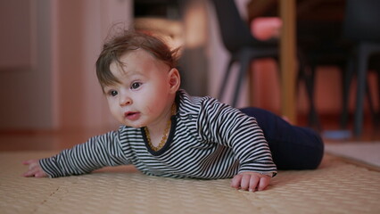 Baby lying on play mat, propped up on arms, curious expression, exploring surroundings,...