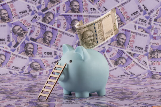 Piggy bank with 500 rupee note of the Republic of India against the background of 100 Indian rupee notes