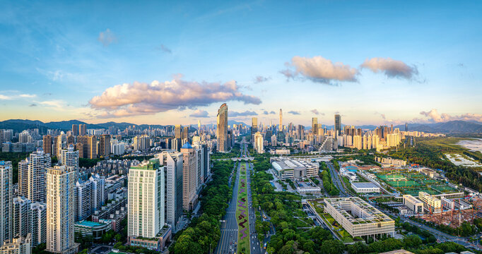 Aerial view of the modern Shenzhen skyline and city center with skyscraper and green park under a clear blue sky at sunset, China.