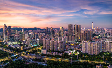 Fototapeta premium Modern skyscrapers and urban skyline glowing at sunset in Shenzhen, China.