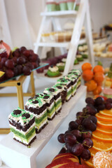 Sponge pieces with cream and fruits on table near grapes and citrus.