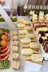Ice cream bars in white chocolate and pastries on stands in wedding dessert area.