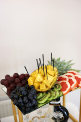 Fruit composition with pineapple grapes kiwi and grapefruit on glass shelf.