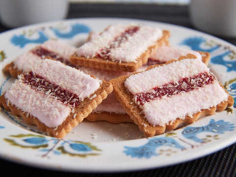 Iced Vo Vo biscuits on a plate with cups in background