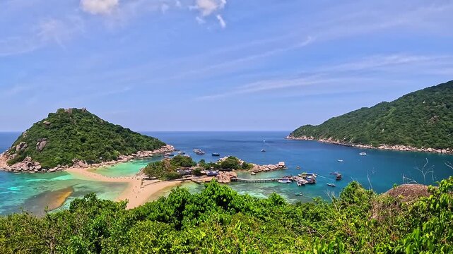 The panoramic video glides over verdant Koh Nang Yuan island (Thailand), showcasing turquoise waters, golden beach, bobbing boats, and thick greenery - mesmerizing tropical vista in sweeping motion!