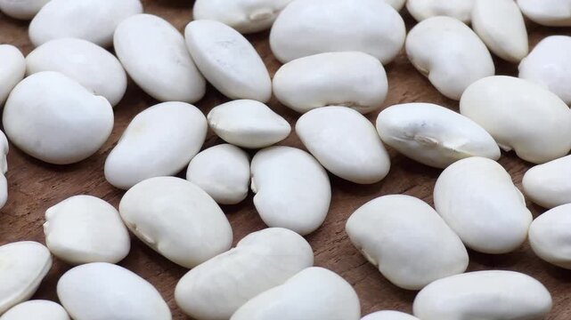 White dry organic butter beans scattered on a wooden surface