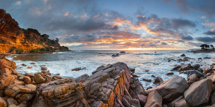 Panorama view of colourful sunrise over a rocky coastline