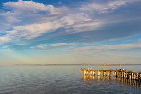 A dramatic sky over a coast jetty and calm ocean in golden hour light