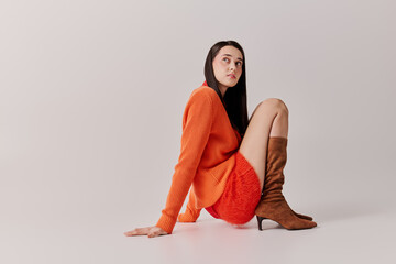 Stylish young woman sits gracefully on the floor, showcasing vibrant autumn fashion choices