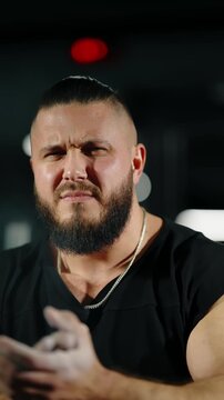 Close-up cinematic frames of a focused, bearded athlete with chalked hands preparing for a heavy lift under moody gym lighting, wearing a black shirt and chain before exertion.
