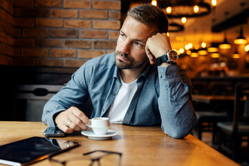 Pensive man drinking coffee thinking in cafe