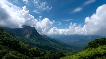 Obraz premium Majestic mountain range with lush green valleys under a bright blue sky with scattered white clouds