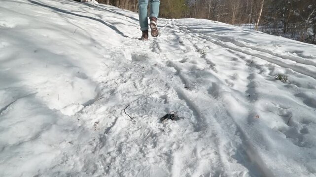 A close-up of a person accidentally dropping their keys while walking in the woods on a winter day, the lost keys fall into the snow