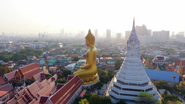 Aerial drone view of giant golden Buddha at Wat Paknam temple with Bangkok skyline in the background. Iconic religious landmark in Thailand.