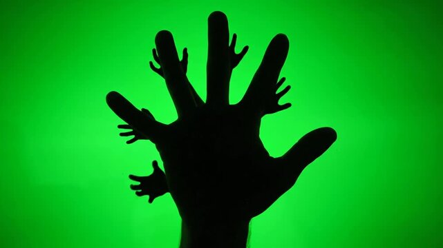 Silhouette of hand against green background.