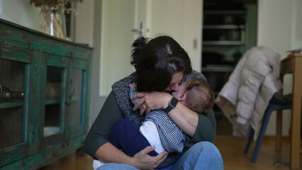 Obraz premium Mother holding baby lovingly on lap, smiling and gazing affectionately, tender bonding moment highlighting warmth and emotional connection in cozy indoor family setting