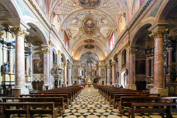 Fototapeta premium Ornate Baroque church interior in Clusone, Italy, with frescoed ceiling, marble columns and wooden pews, bathed in warm light. Symmetrical and peaceful sacred space.