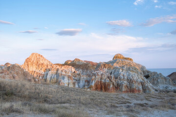 Fototapeta premium Scenic panorama of Cape Shekelmes on the shore of Lake Zaisan in East Kazakhstan region. Unique clay canyons with bright stripes of ochre