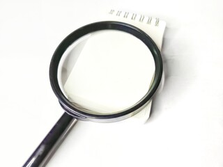 Magnifying glass and blank notebook on white background