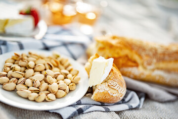 White plate filled with salted pistachios. Healthy snack, perfect for a picnic outdoors. Food photography with short depth of field.