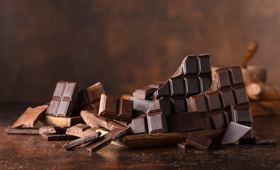Broken bitter and milk chocolate bars on a brown background.