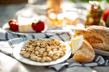 White plate filled with salted pistachios. Healthy snack, perfect for a picnic outdoors. Food photography with short depth of field.