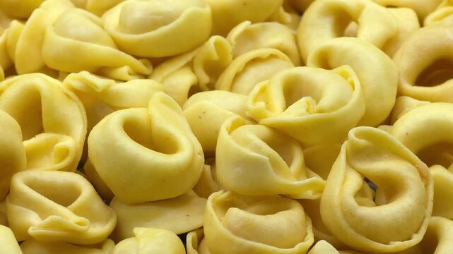 Traditional italian yellow raw tortellini pasta background macro close up