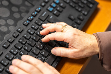 Close up of senior woman hands typing on computer keyboard. Home office or everyday digital communication concept.