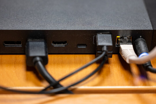 Close up of media device back panel with HDMI, USB and Ethernet cables connected. Home electronics setup and digital connectivity concept.