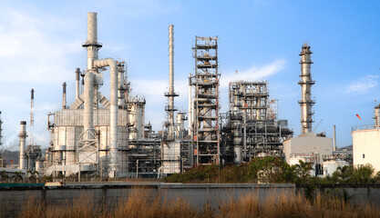 Fototapeta premium Exterior view of a modern oil refinery factory, industrial engineering concept.Oil and gas refinery plant with distillation towers against a clear blue sky.