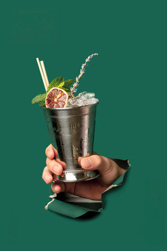 Hand Holding Metal Mint Julep Cup with Crushed Ice and Lavender through Green Paper