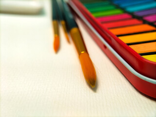 Fototapeta premium A watercolor set with vibrant colors is displayed on a white table. 