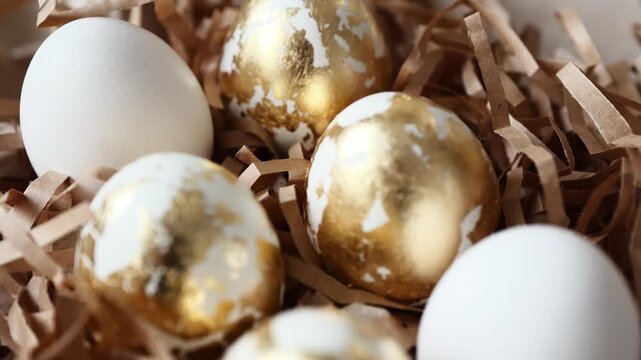 Four eggs covered in gold resting on crinkled brown paper in a basket for spring events.