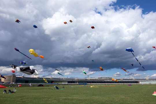 Kites flying over Tempelhof Airport during kite festival under large clouds