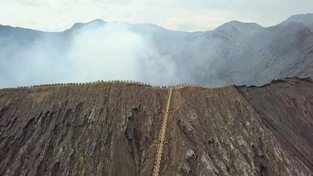 Stunning aerial view of Mount Bromo emitting white smoke alongside Mount Batok in East Java, Indonesia. Majestic volcanic landscape at Bromo Tengger Semeru National Park during a clear morning.