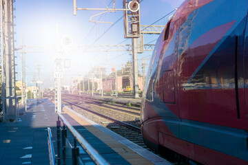 passenger train at railway station texture background red modern locomotive on tracks urban transport infrastructure sunny day perspective concept of travel industry, public transport, logistics © Lana Pietukhova