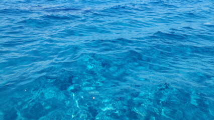 Fototapeta premium Calm Blue Ocean Water With Gentle Waves And Clear Visibility To Underwater Rocks