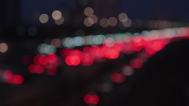 Blurred city street scene at night featuring bokeh lights from cars and streetlights.