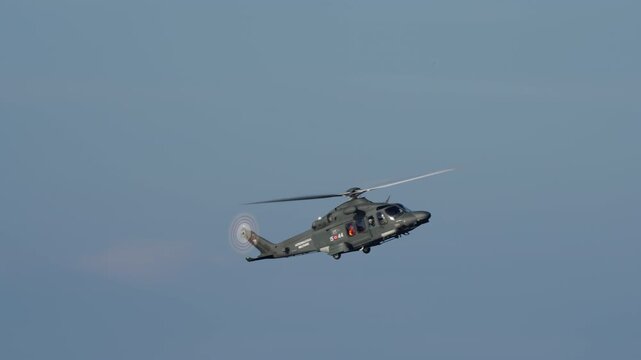 LUQA, MALTA - SEPTEMBER 28, 2025: An Armed Forces of Malta AgustaWestland AW139 military helicopter flies across a clear blue sky. The camera pans to follow the aircraft, showing its spinning main and
