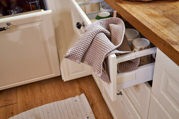 Open kitchen drawer with towel caught in it in messy modern interior. Unfinished household chores...