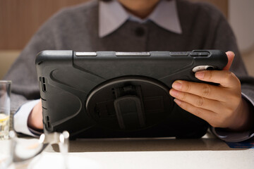 Student holding a black tablet computer while focusing on operation