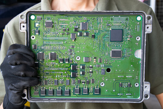 The mechanic is holding the ECU box, which is the car's main brain.