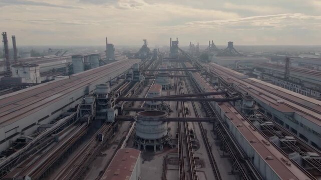 A dramatic perspective shot looking down a series of long, parallel industrial buildings or train carriages. The repetitive lines and metallic textures create a strong sense of industrial scale and lo